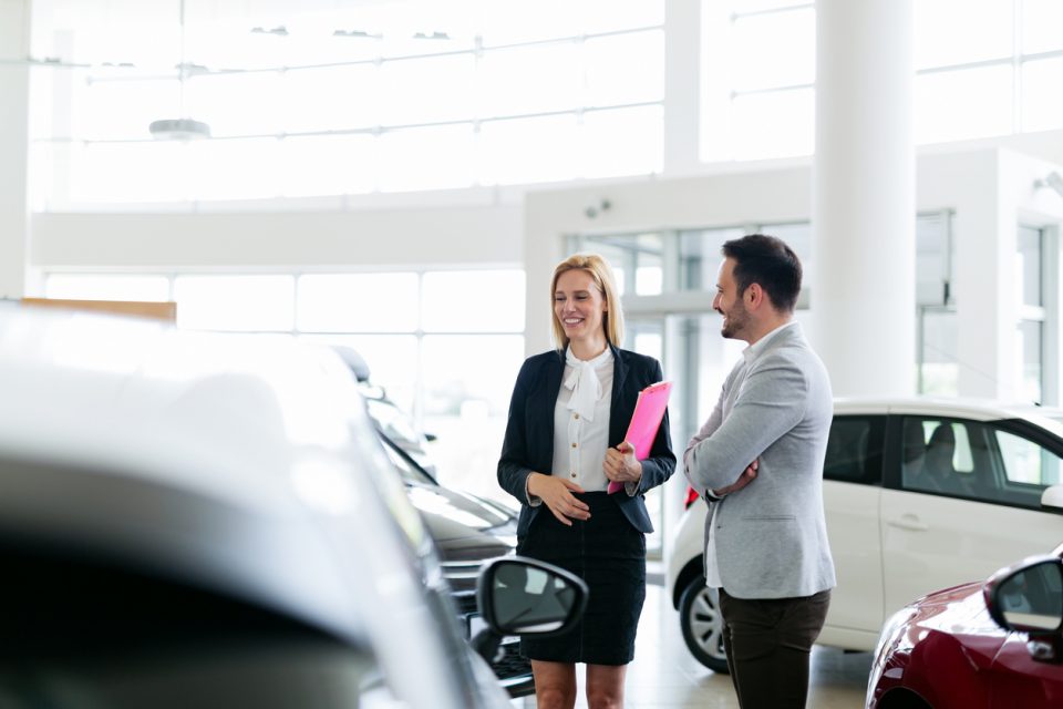 Professional salesperson selling cars at dealership to buyer