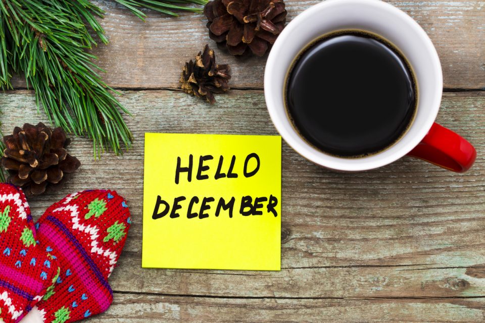 Hello December- handwriting in black ink on a sticky note with a cup of coffee and mittens, New Year resolutions concept