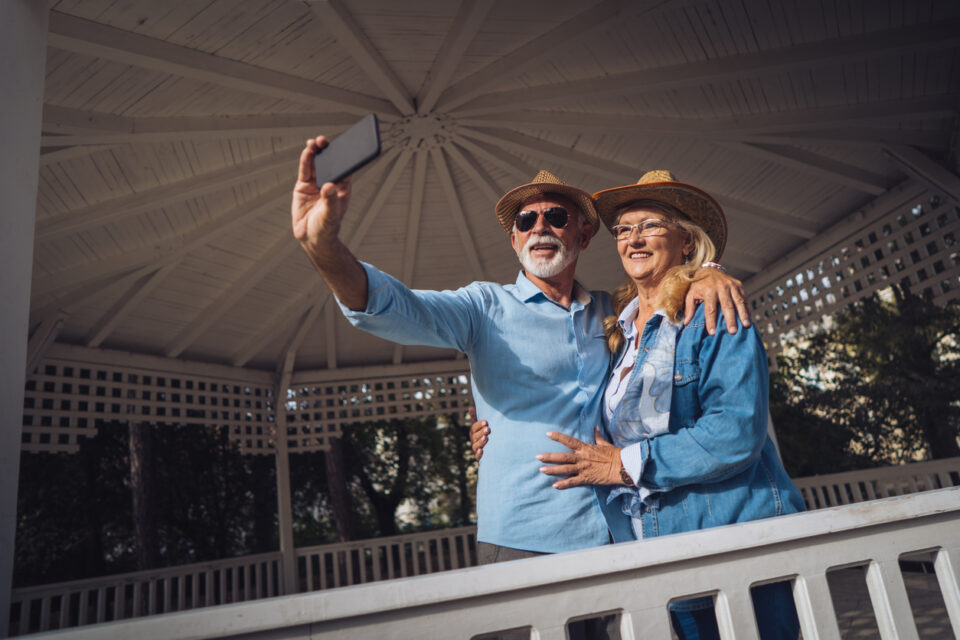Active senior couple is taking selfie with smart phone on their journey.