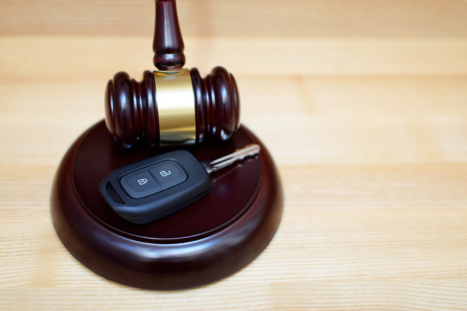 Judges gavel, sounding block and car key on light wooden background with copy space. Car auction, legal trial of traffic accident, traffic law and justice concept.