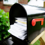 Black mailbox outside filled with mail